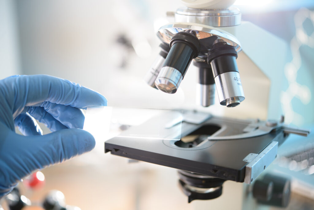 Scientist placing a slide beneath an optical microscope